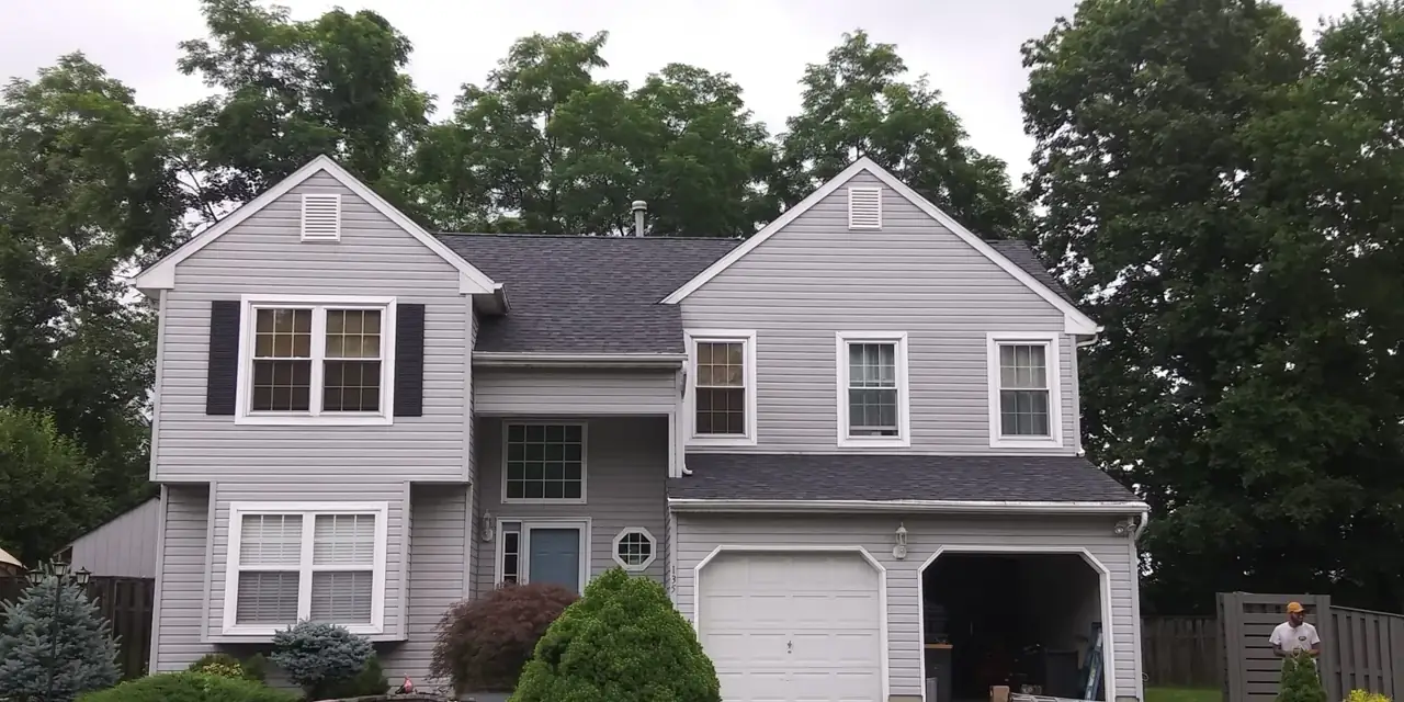 Front of a colonial home after a new dark shingle roof
