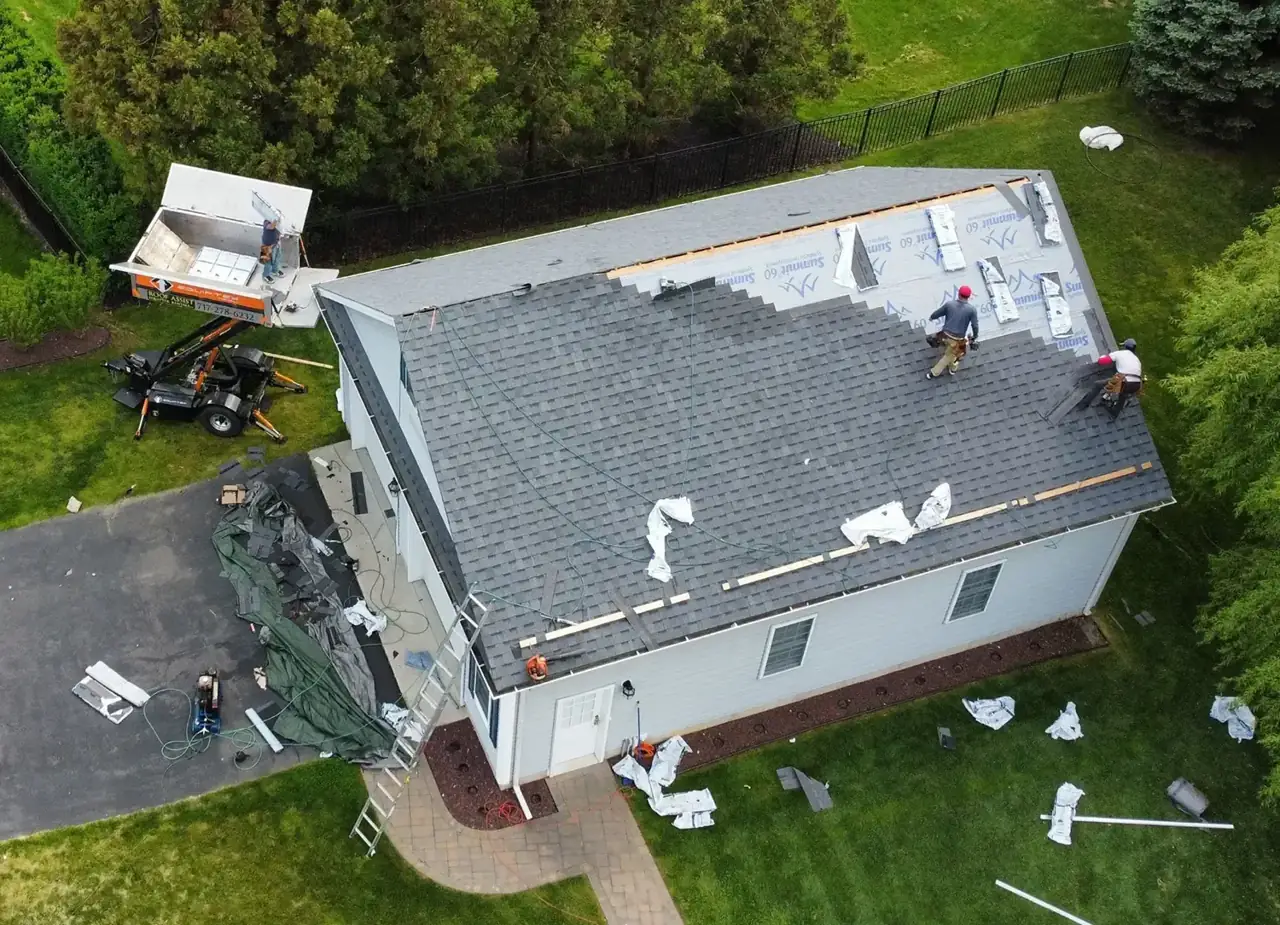 Overhead view of crew tearing off and re-roofing a ranch home