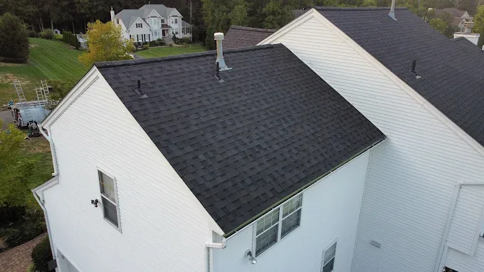 Repaired dark shingle roof on a white gable-end home