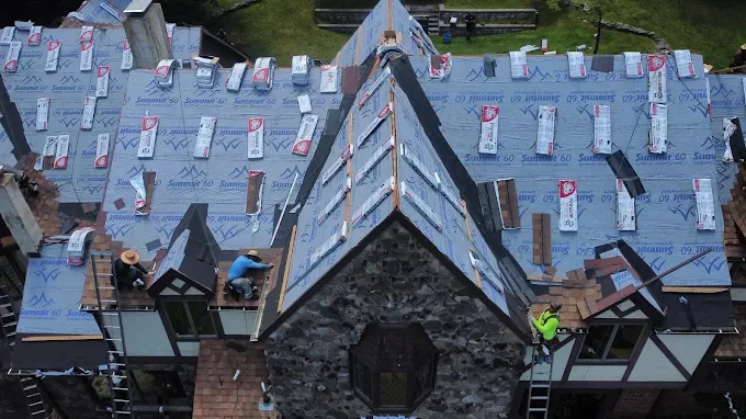 Allabaugh Construction crew installing synthetic underlayment over a stripped roof deck