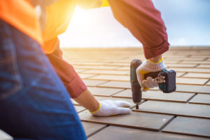 Gray roof - Repair and Replace the House Roof with Handyman with Tools and Pprotective equipment. Stand on the Roof with the Sky Background.