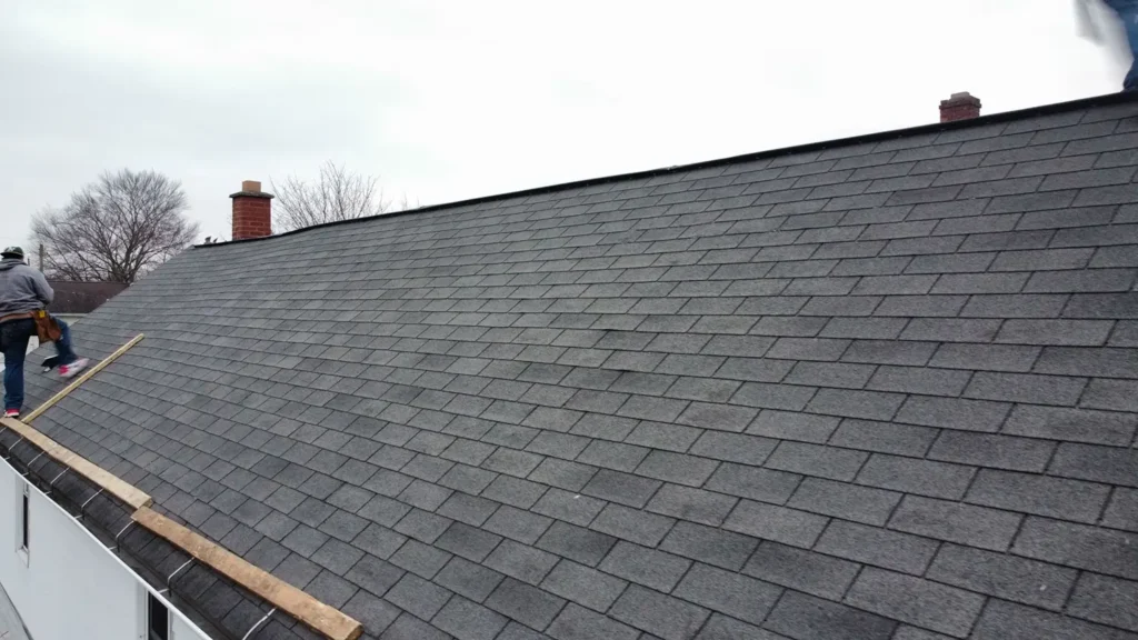 A close-up of a newly installed residential roof. A man is standing on the roof to complete the project.
