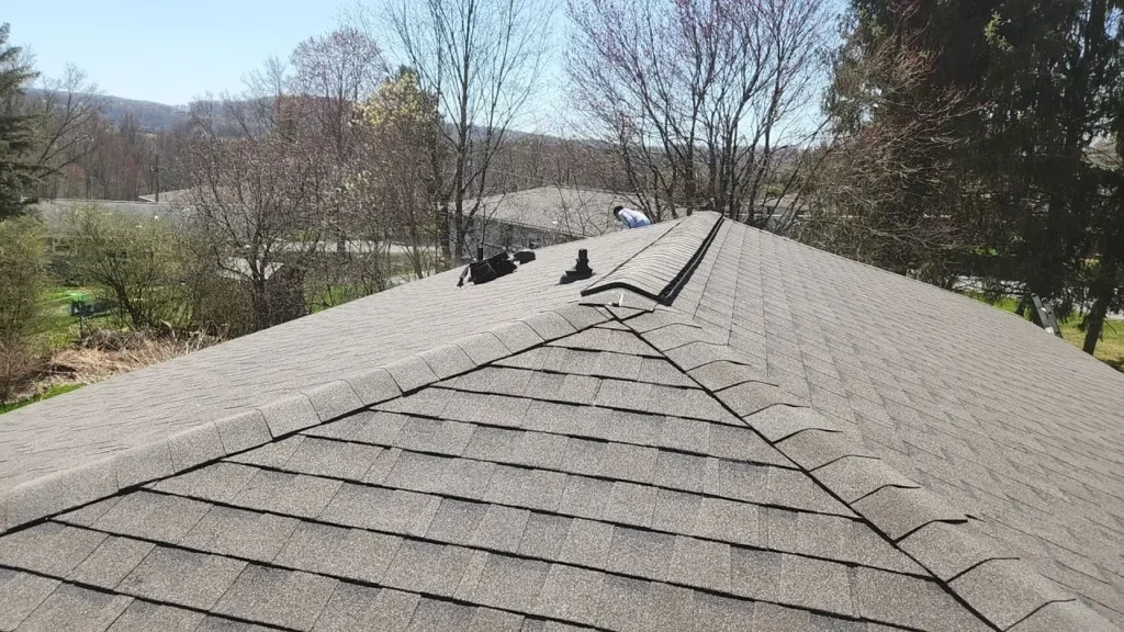 A newly-installed roof with an installer working on the far side of the roof.