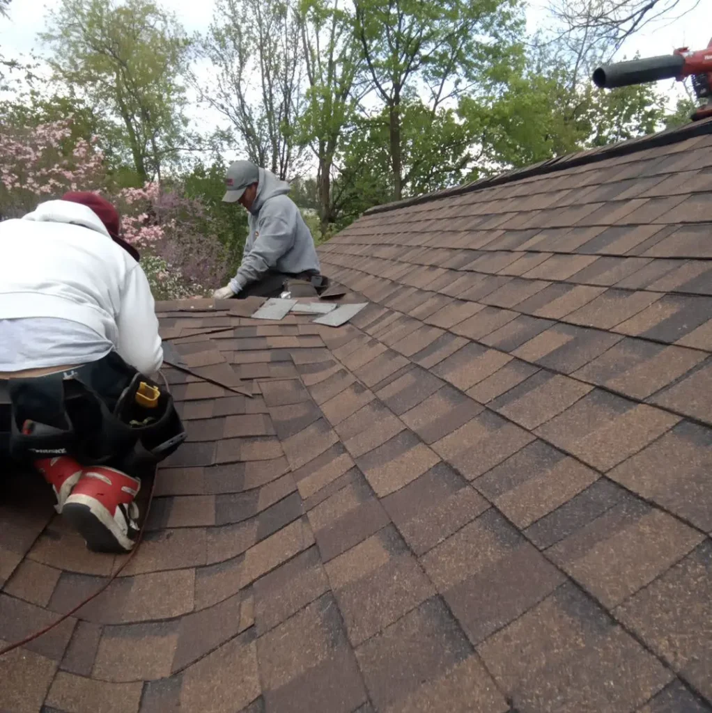 Two men installing new roof shingles on a home.